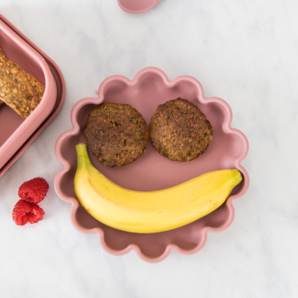 Raspberry sorbet baby flower plate with an unopened banana on top and two weetabix muffins, creating a face